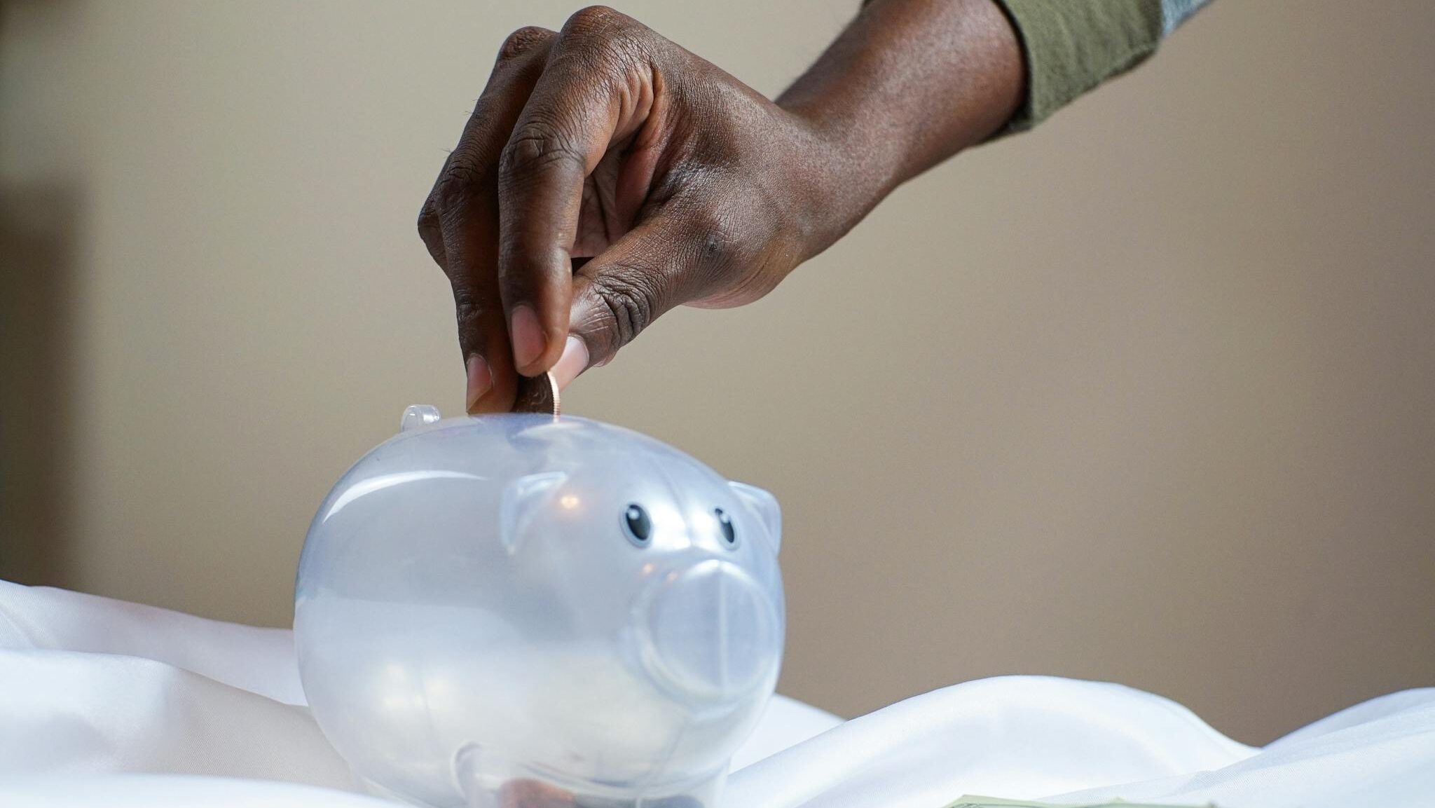 Person Putting Coin in a Piggy Bank